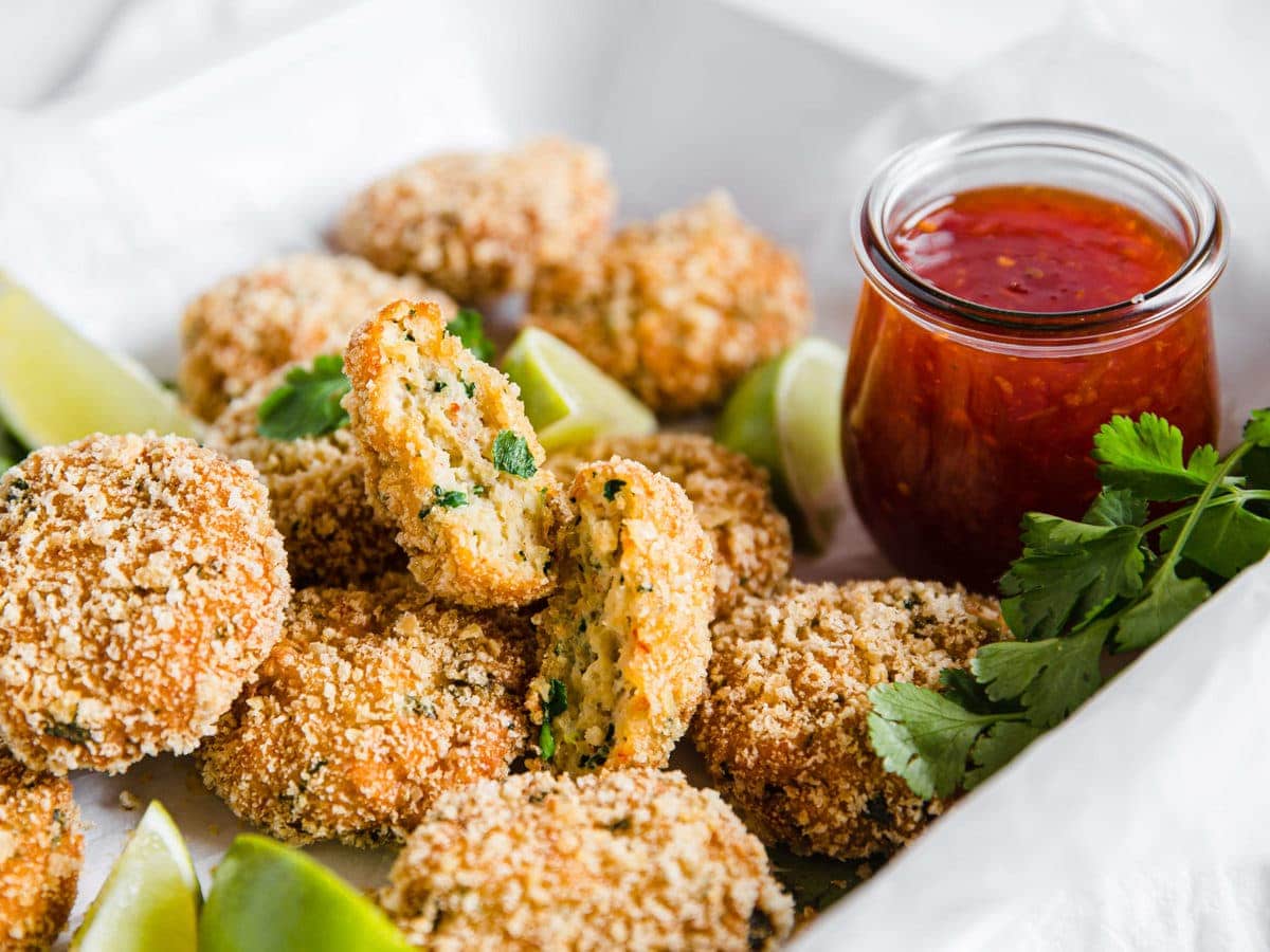 gluten free shrimp cakes plated with sweet chili sauce and limes