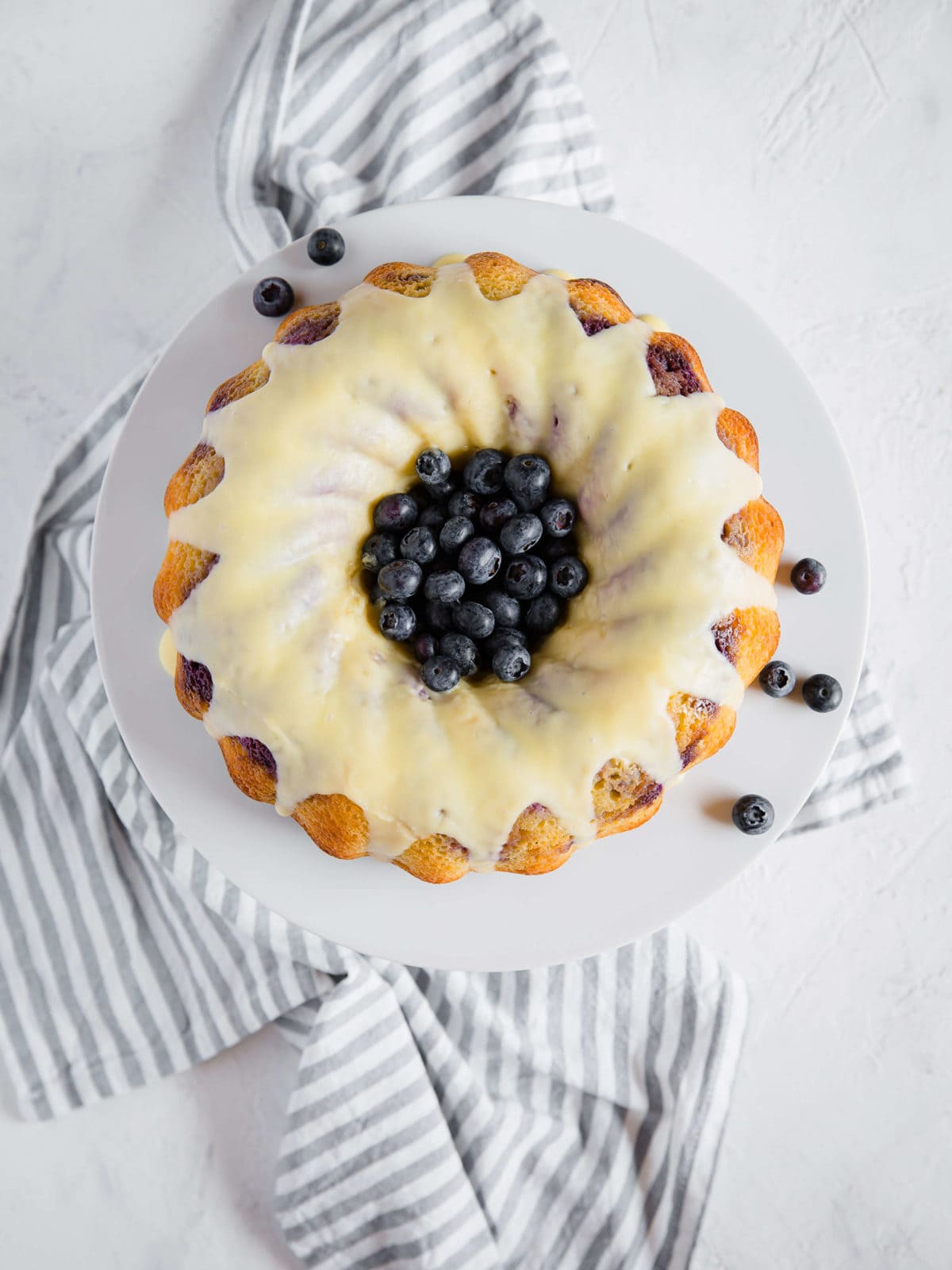 Overhead shot of a blueberry lemon pound cake, with lemon glaze and garnished with fresh blueberries