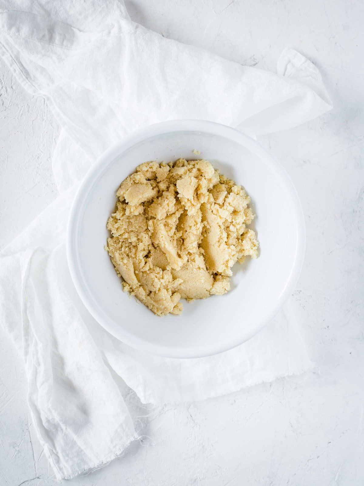 a white mixing bowl with blanched almond flour mixed with eggs and sweetener to make a pie crust.