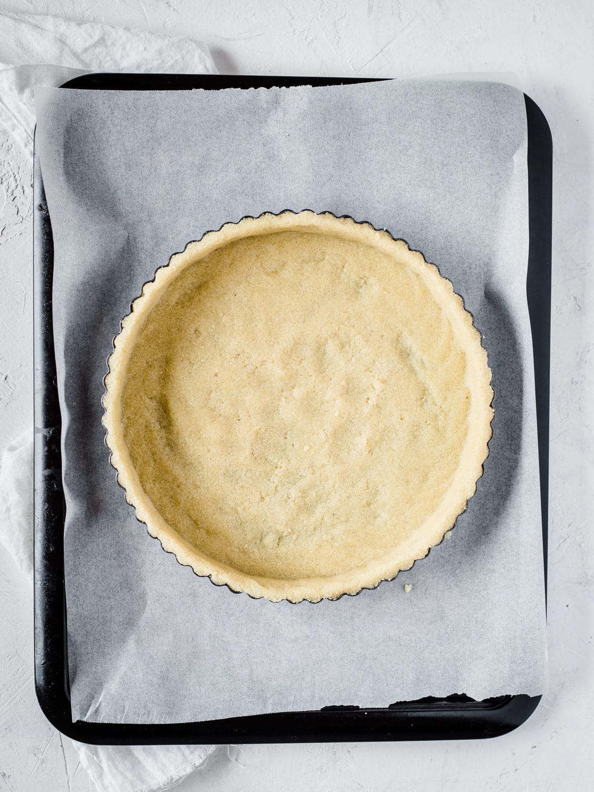 a gluten free and low carb pie crust, pressed into a tart pan, ready to be baked.
