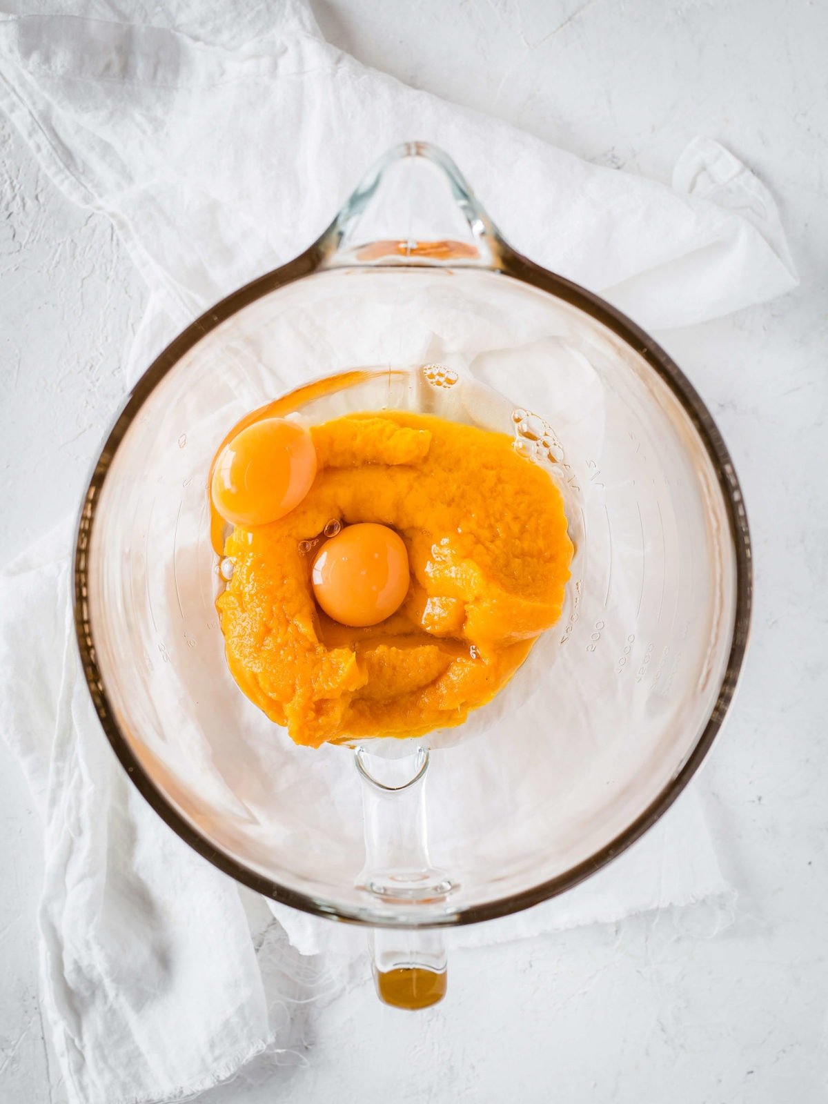 a measuring cup with eggs and pumpkin puree in it. 