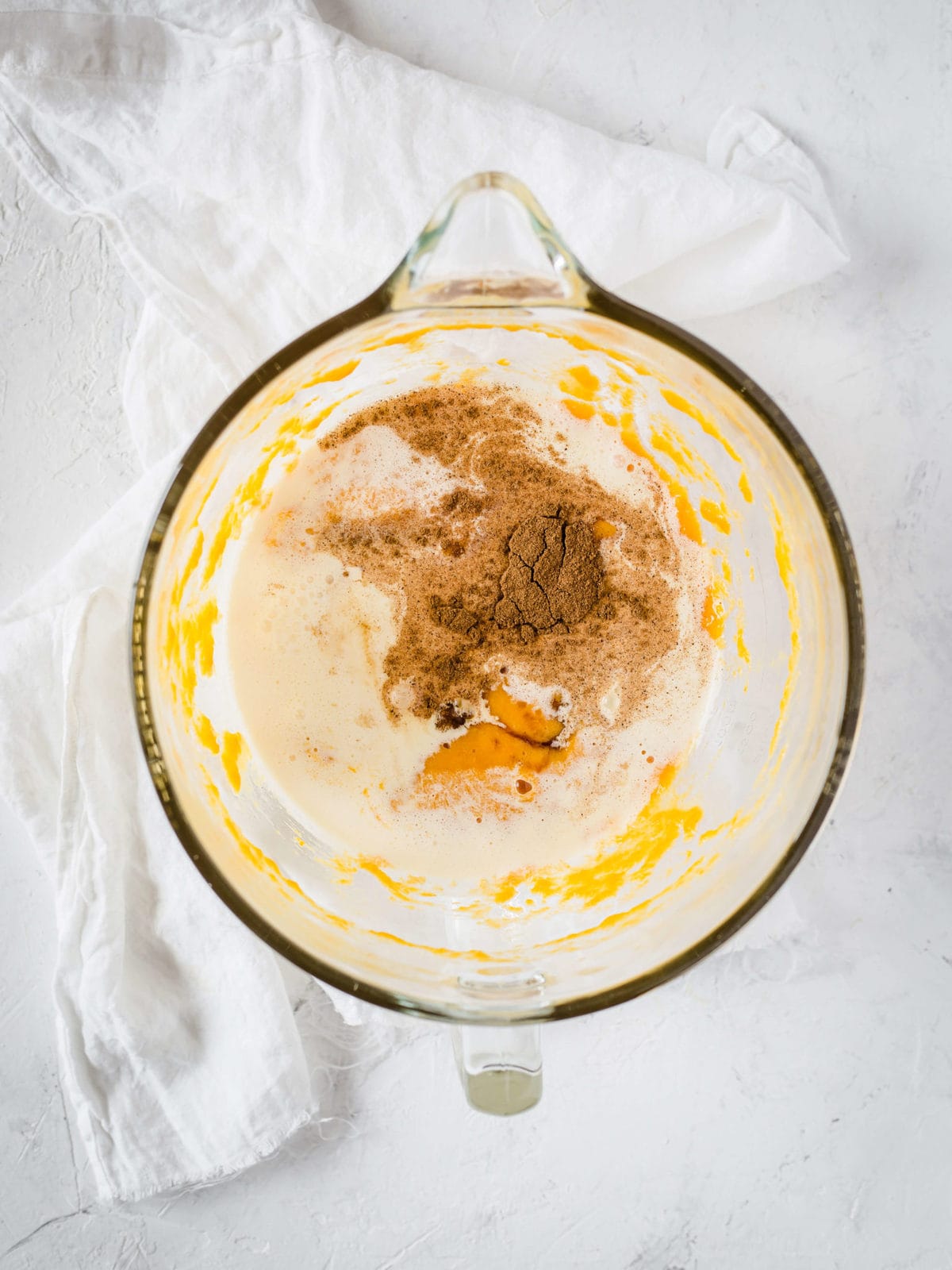 a measuring cup with eggs, pumpkin puree, cream, sweetener and eggs in it.  