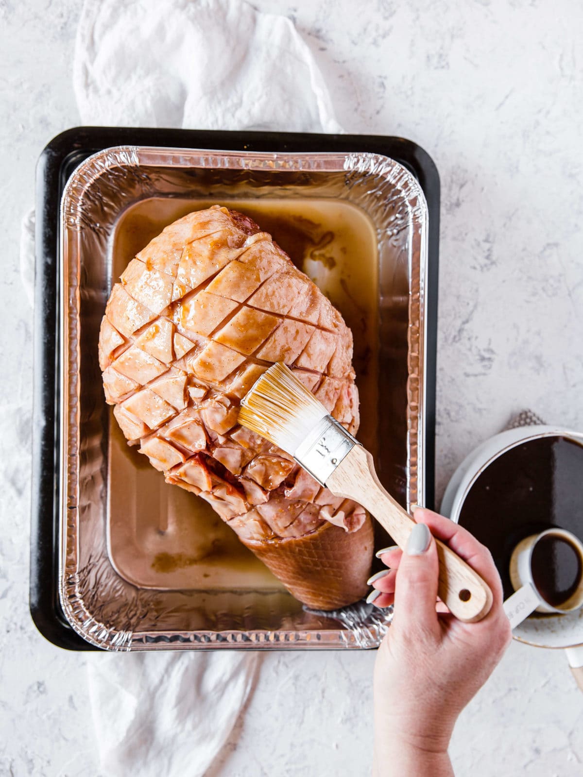 brushing a sugar free keto glaze on top of a holiday ham