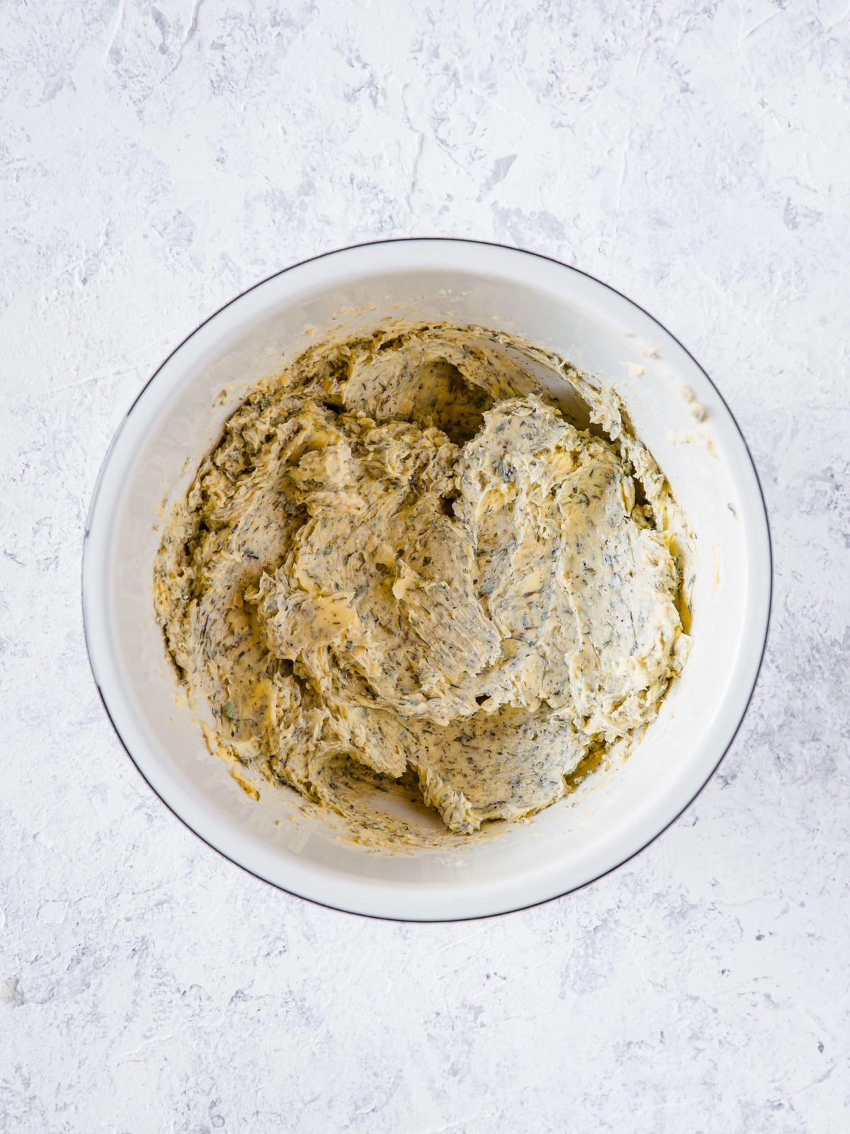 A small mixing bowl with butter, thyme, sage, minced onion, salt, and pepper all mixed up. 