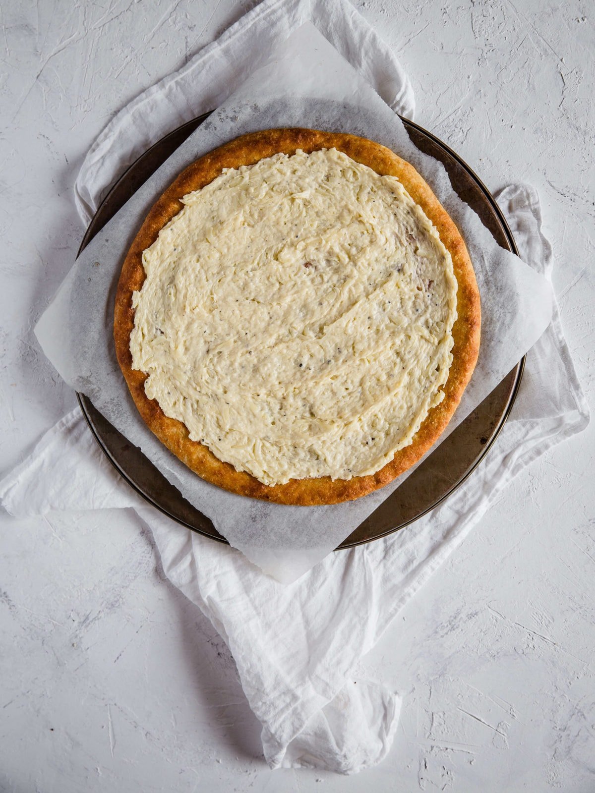 overhead shot of a low carb pizza crust, topped with cream sauce