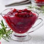 A glass gravy boat full of fresh made cranberry sauce.