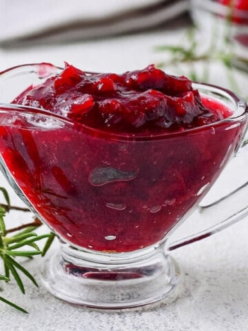 A glass gravy boat full of fresh made cranberry sauce.