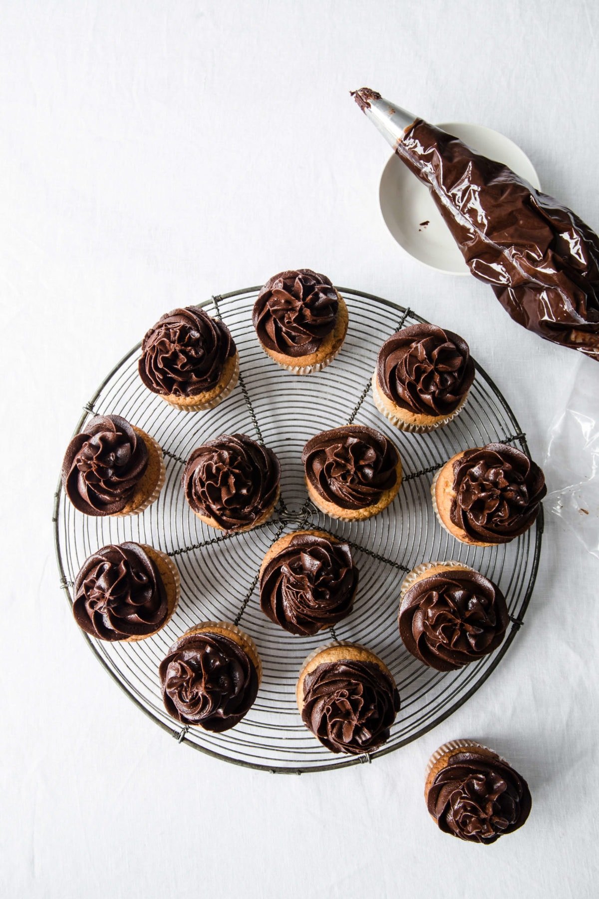 Chocolate frosting on vanilla cupcakes - plated on a cooling rack