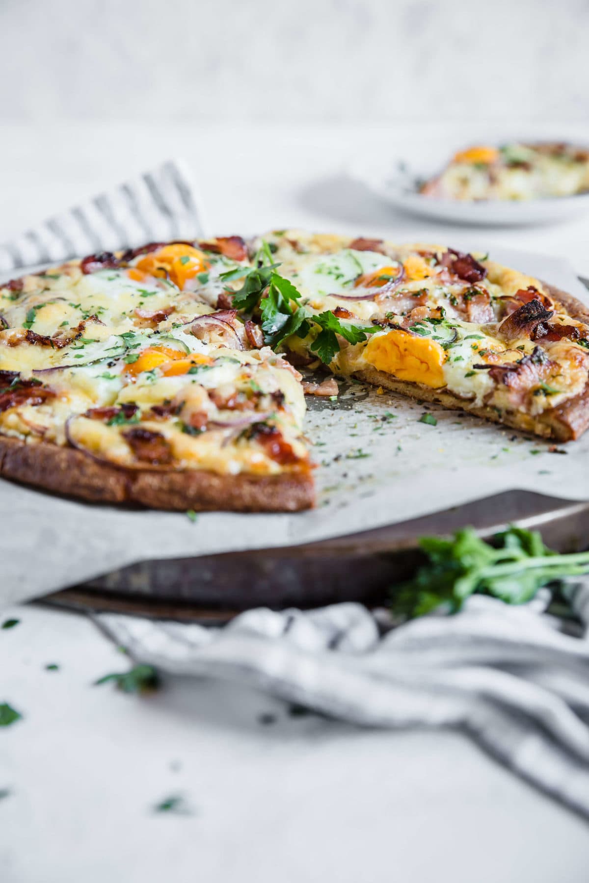 overhead shot of a low carb pizza crust, topped with cream sauce and bacon, cheese, and eggs