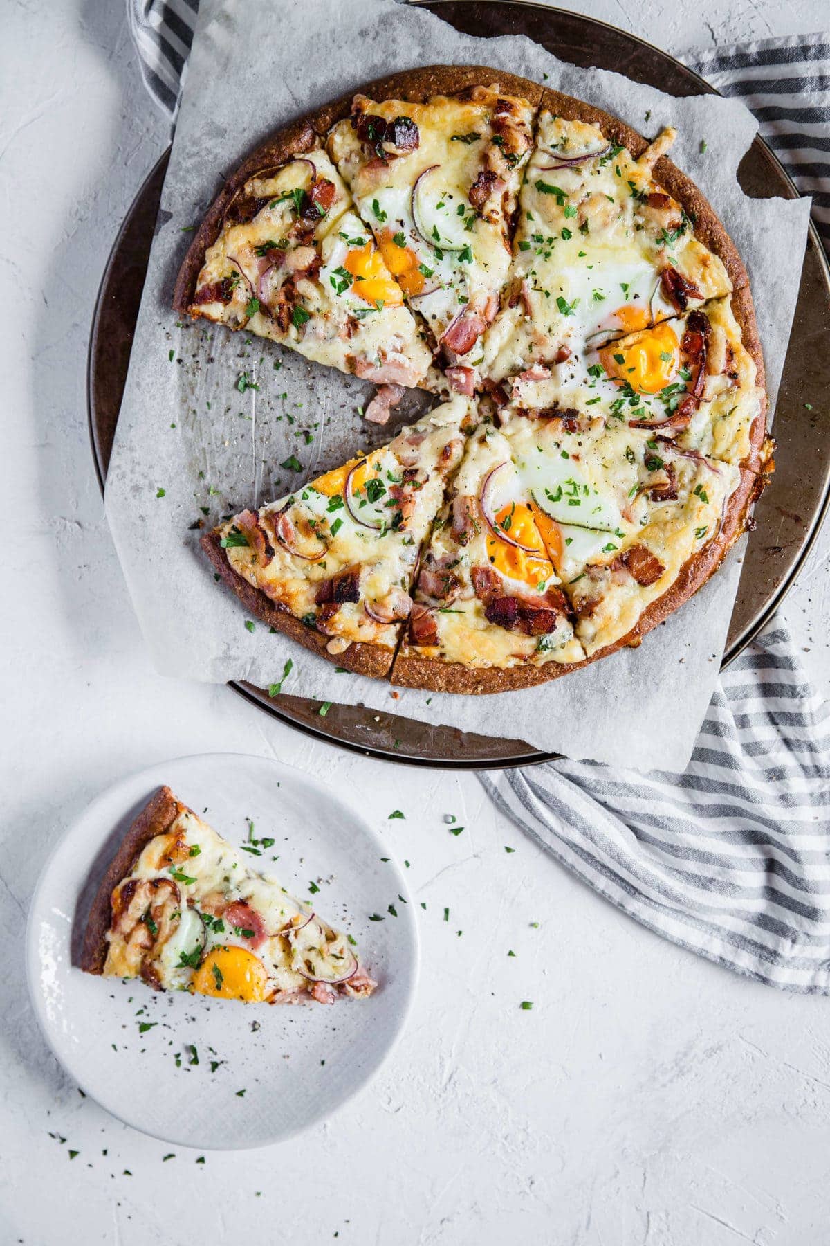 a pizza pan, lined with parchment paper holding a low carb breakfast pizza