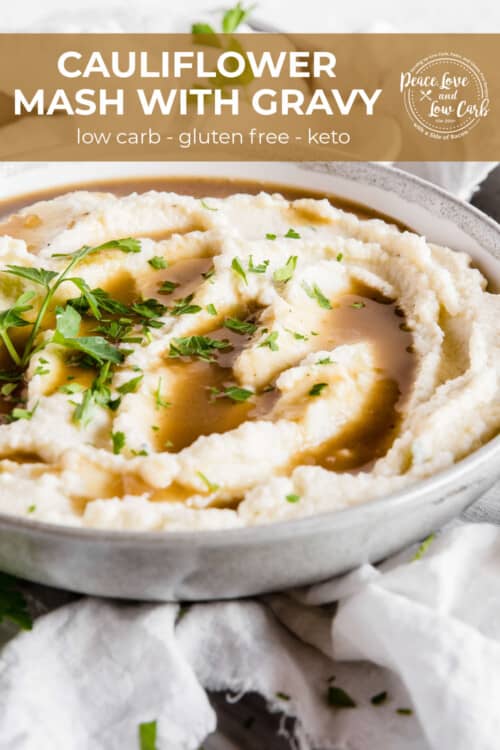 A ceramic bowl full of a creamy mashed cauliflower with pan gravy and garnished with parsley.