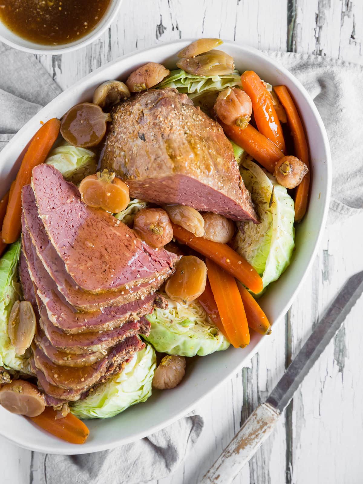 A casserole dish with sliced corned beef, cabbage, carrots, radishes and parsley.