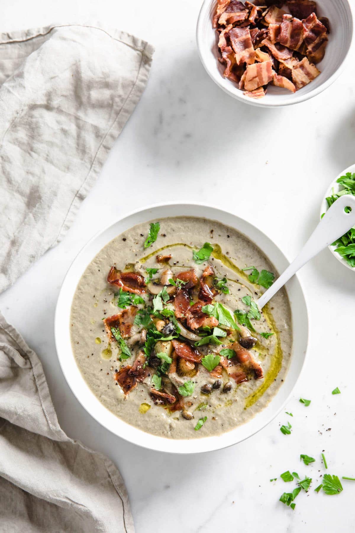 Overhead picture of a bowl of soup, garnished with bacon, parsley and olive ol