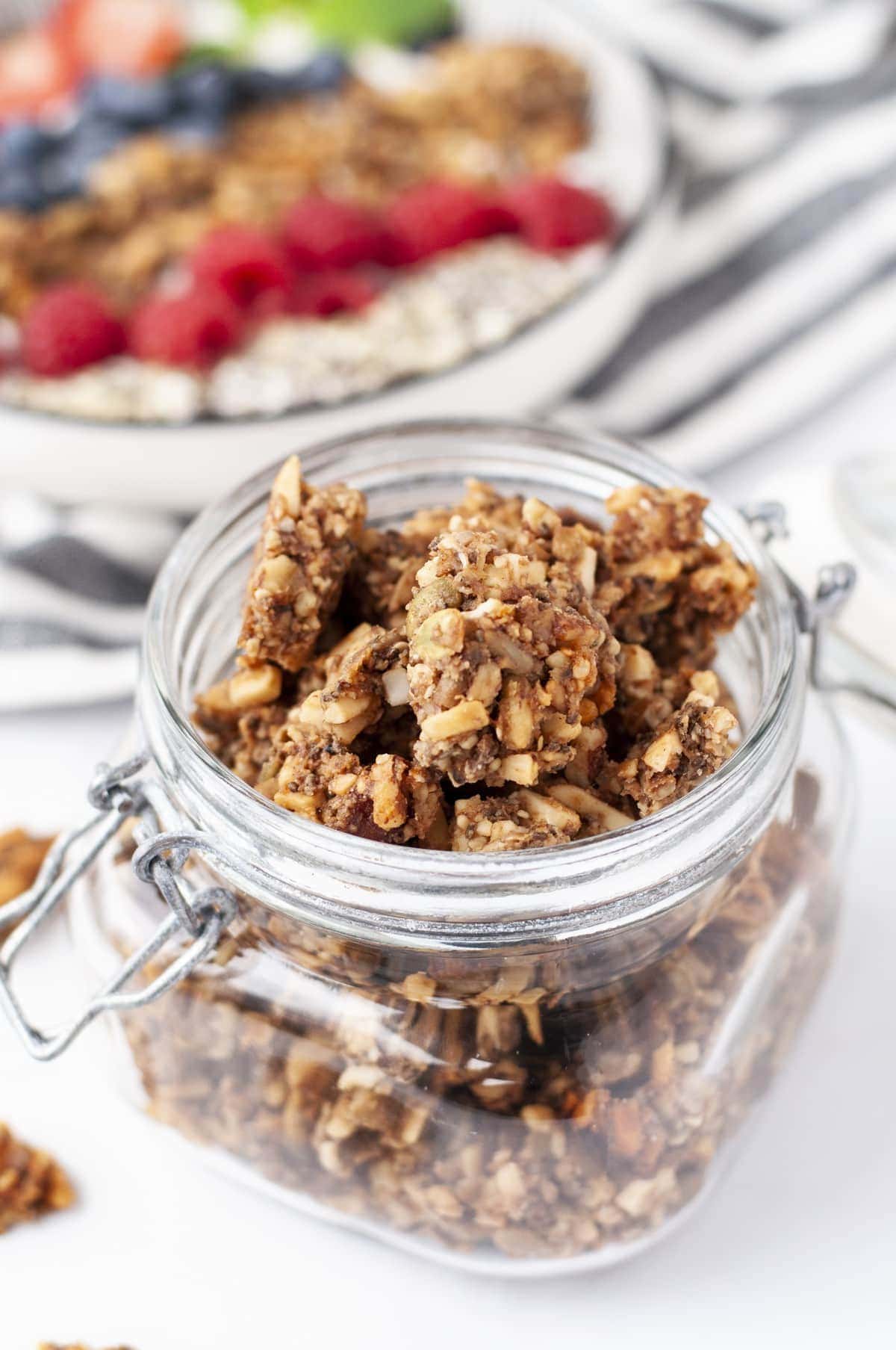 a jar of gluten free granola with fresh fruit and yogurt