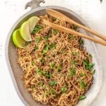 sesame ginger noodles, topped with green onions, sesame seeds and lime wedges, served on a large platter