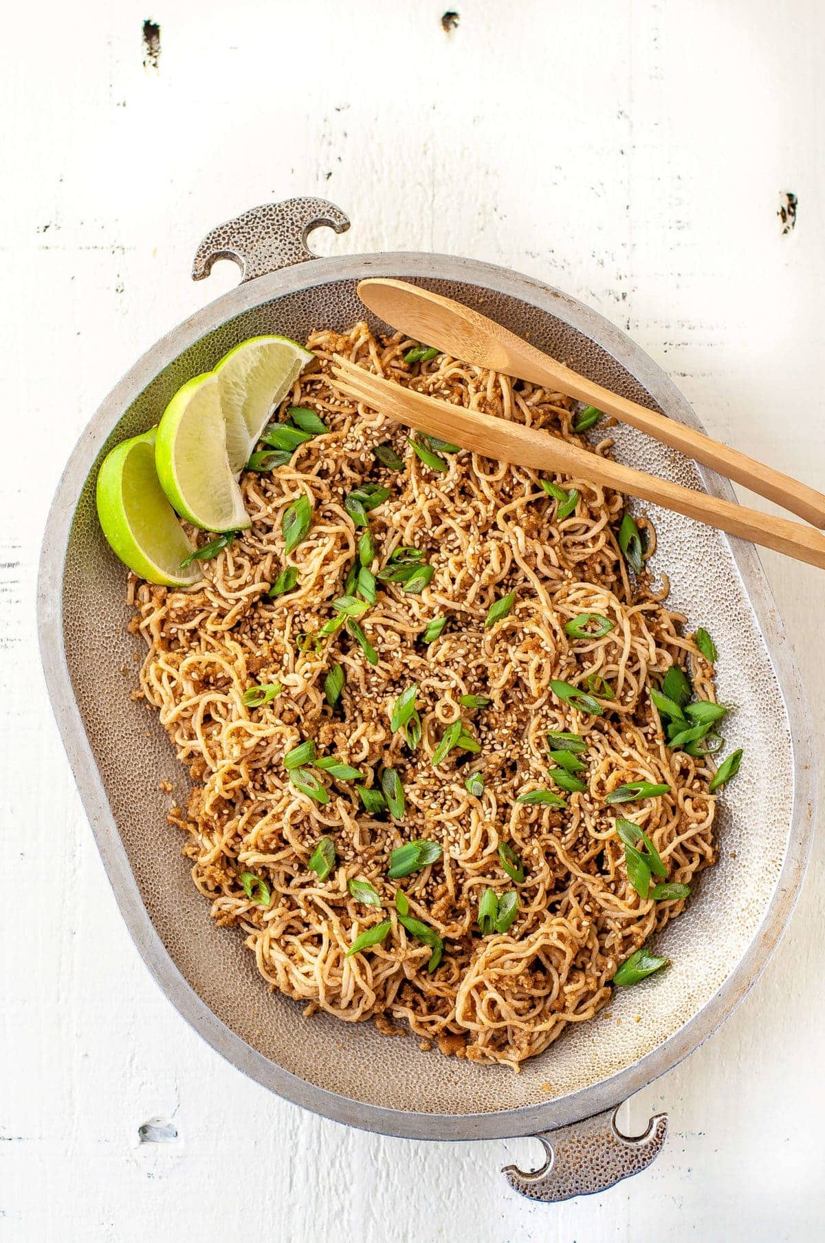 sesame ginger noodles, topped with green onions, sesame seeds and lime wedges, served on a large platter