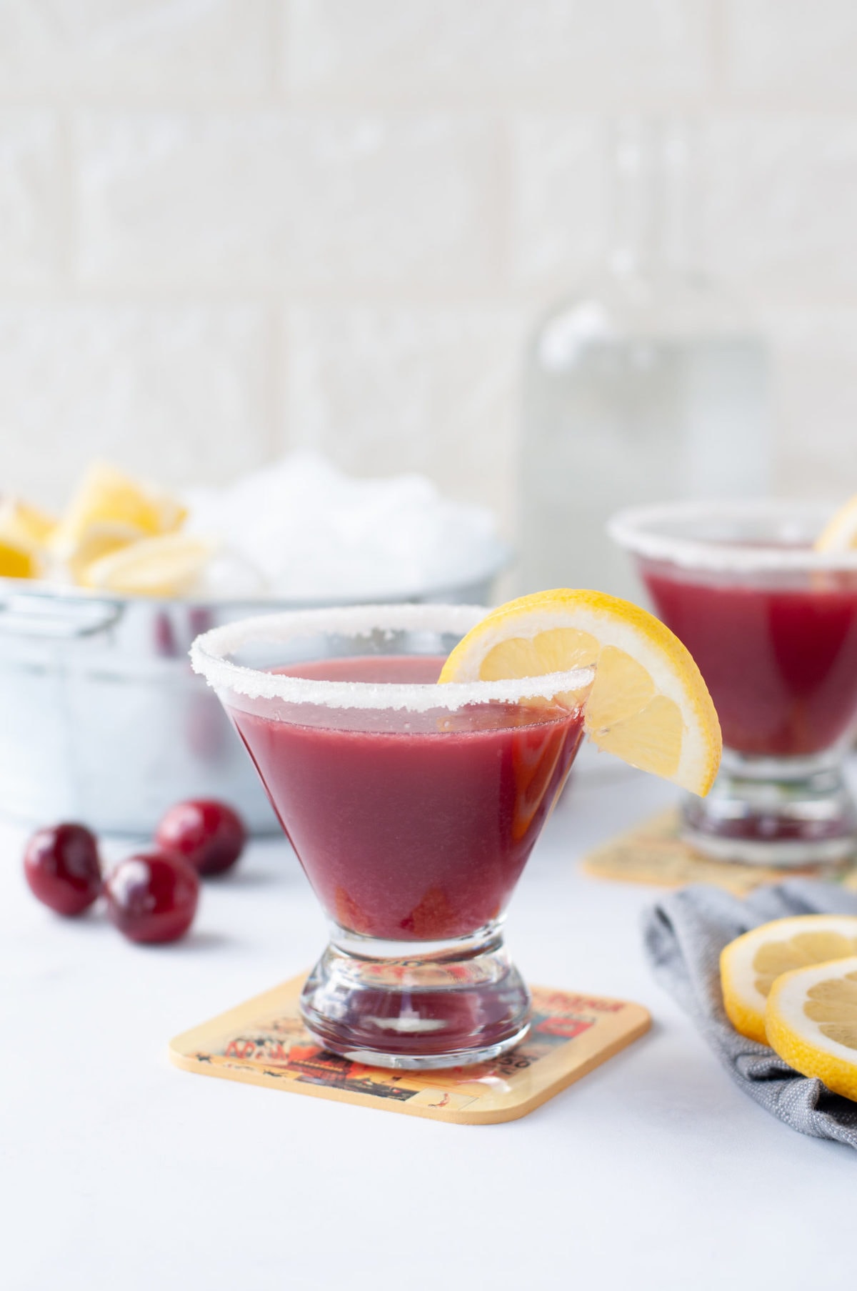 a stemless martini glass filled with a tart cherry lemon drop, garnished with a sugar rim and a lemon