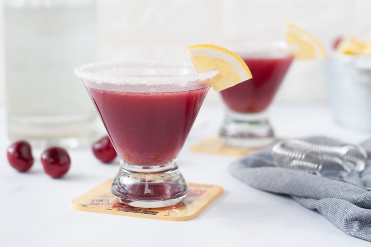 a stemless martini glass filled with a tart cherry lemon drop, garnished with a sugar rim and a lemon