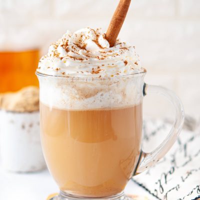 keto hot buttered rum cocktail in a clear glass mug, topped with whipped cream and a cinnamon stick