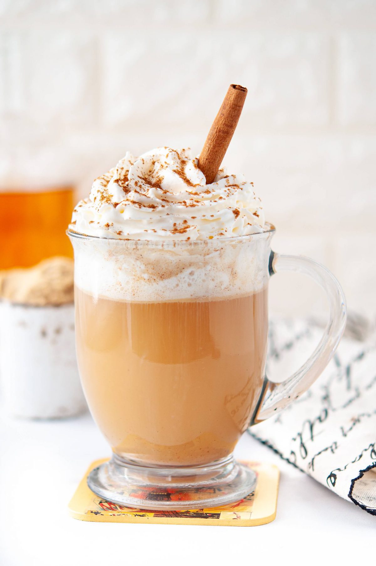 keto hot buttered rum cocktail in a clear glass mug, topped with whipped cream and a cinnamon stick