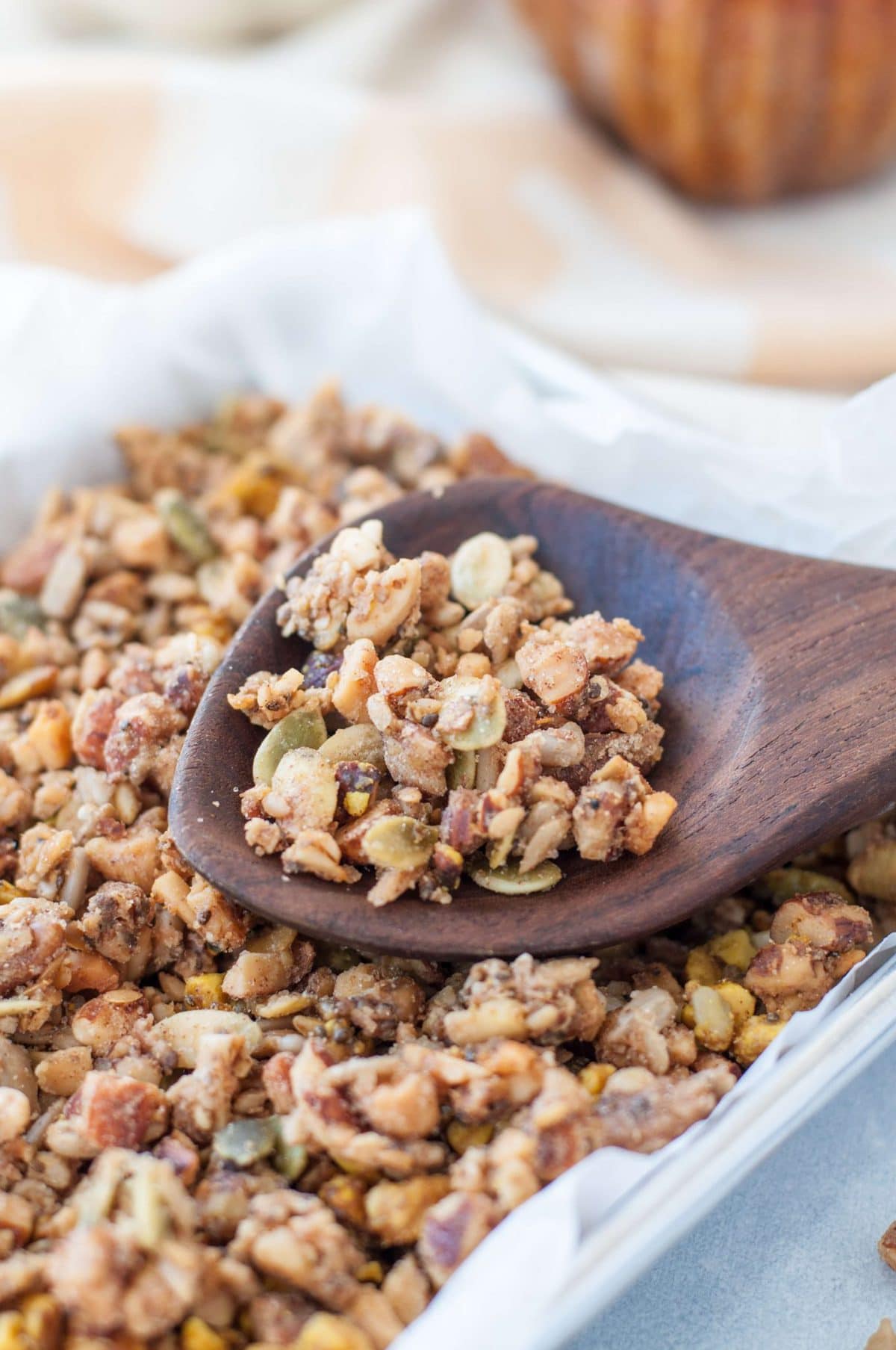 Granola fresh out of the oven on a baking sheet with a wooden spoon