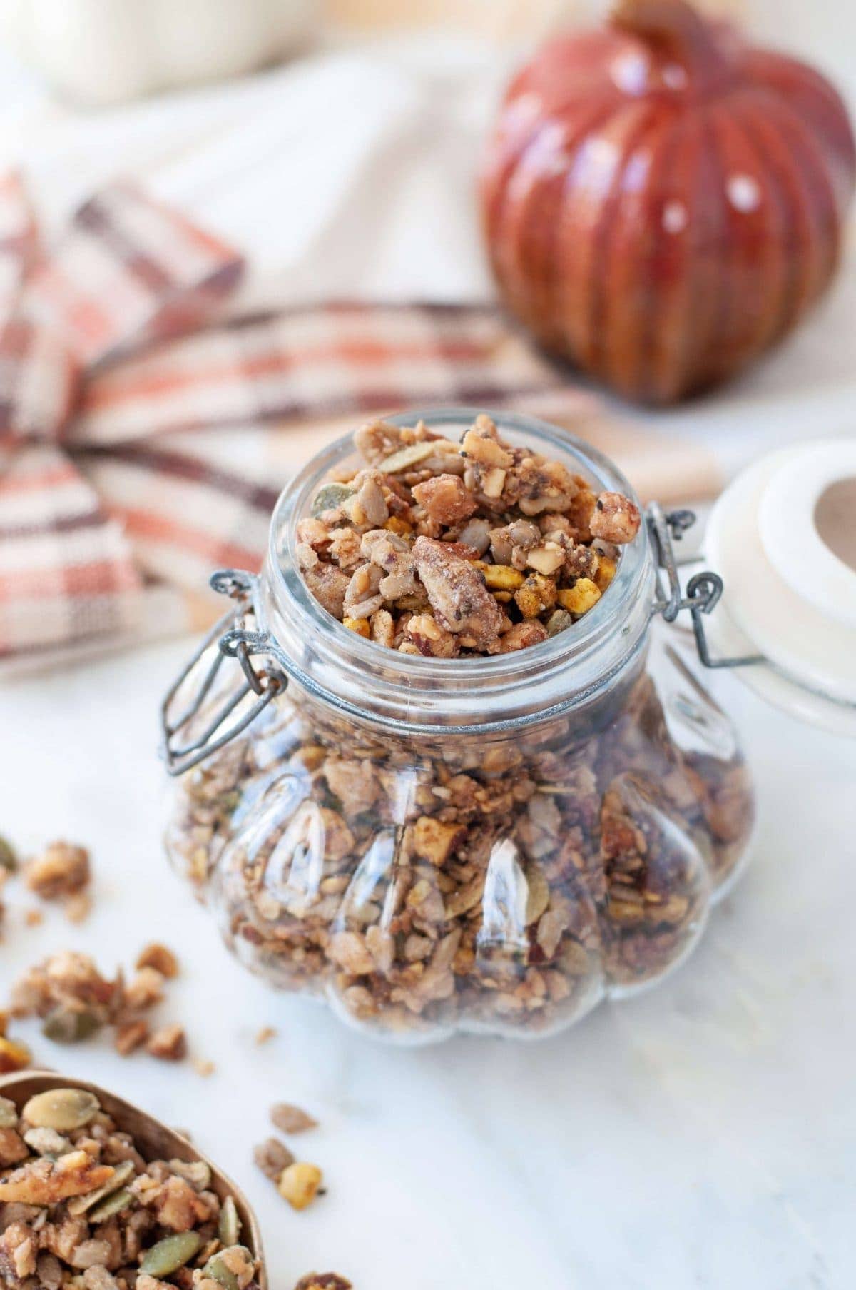 Gluten Free Pumpkin Spice granola in a decorative glass jar, shaped like a pumpikin