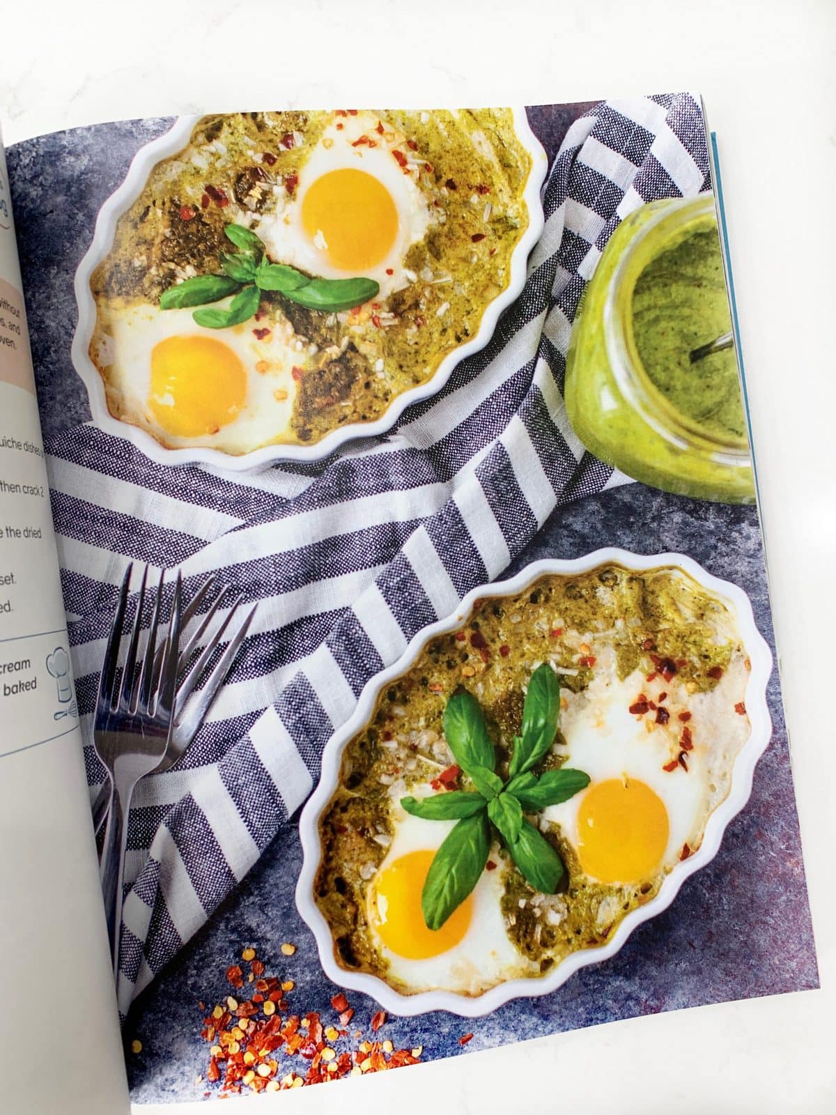 flat lay of a breakfast recipe in a cookbook - pesto baked eggs