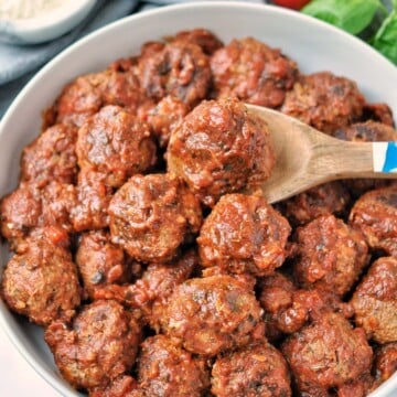 Overhead shot of slow cooked meatballs in tomato sauce. surrounded by fresh ingredients
