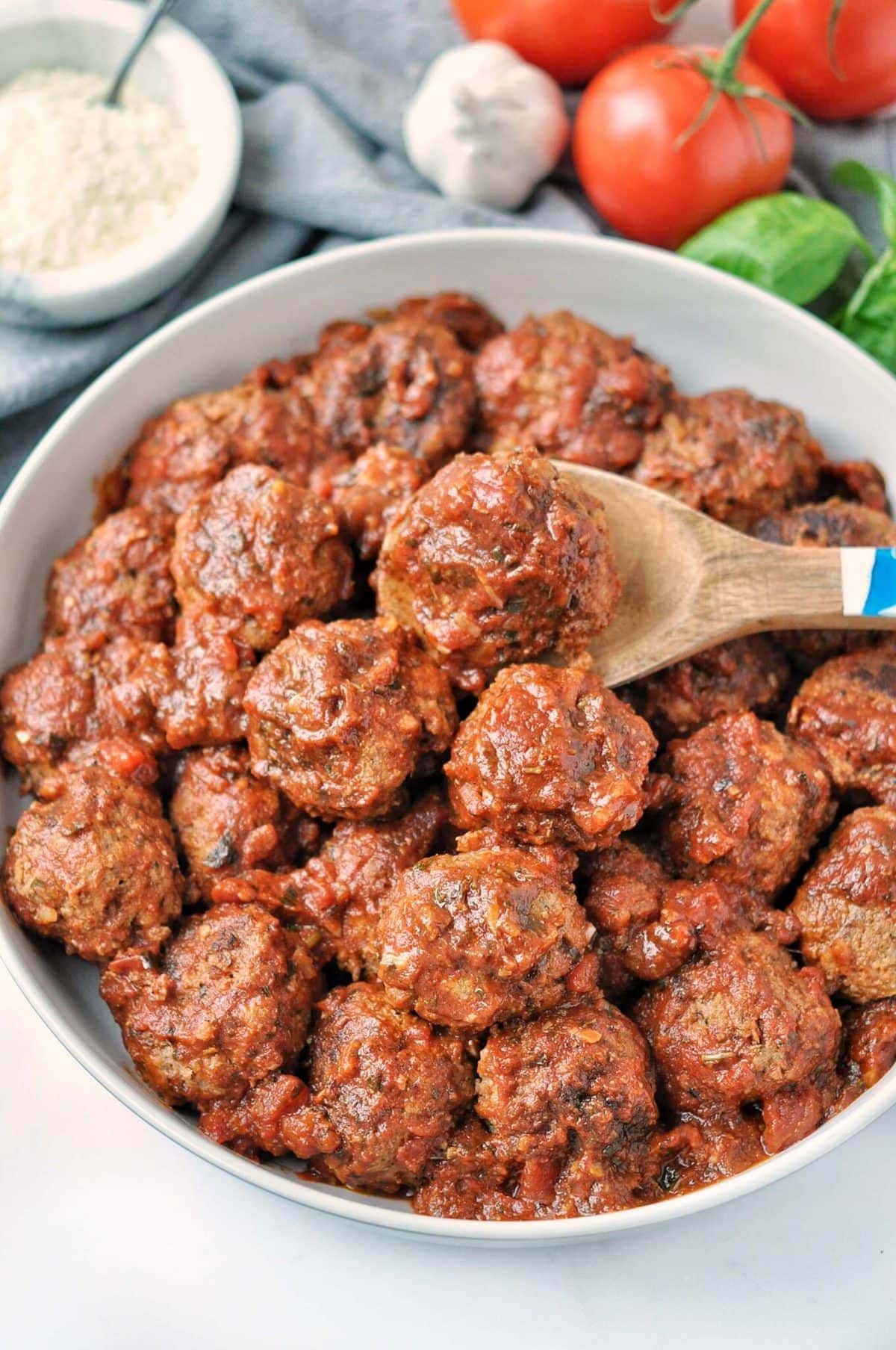 Overhead shot of slow cooked meatballs in tomato sauce. surrounded by fresh ingredients