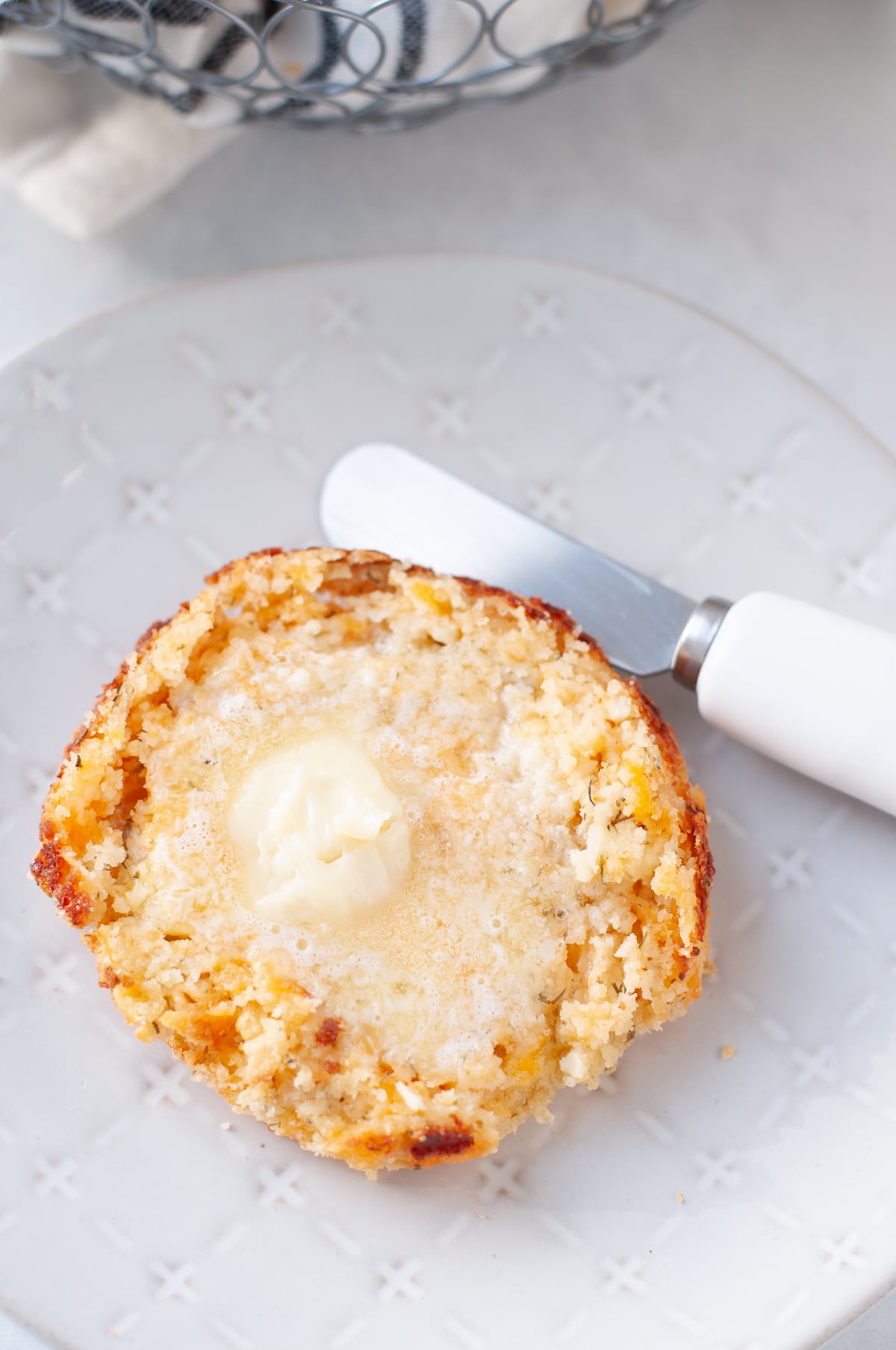 overhead shot of a keto cheddar biscuit slathered with melted butter