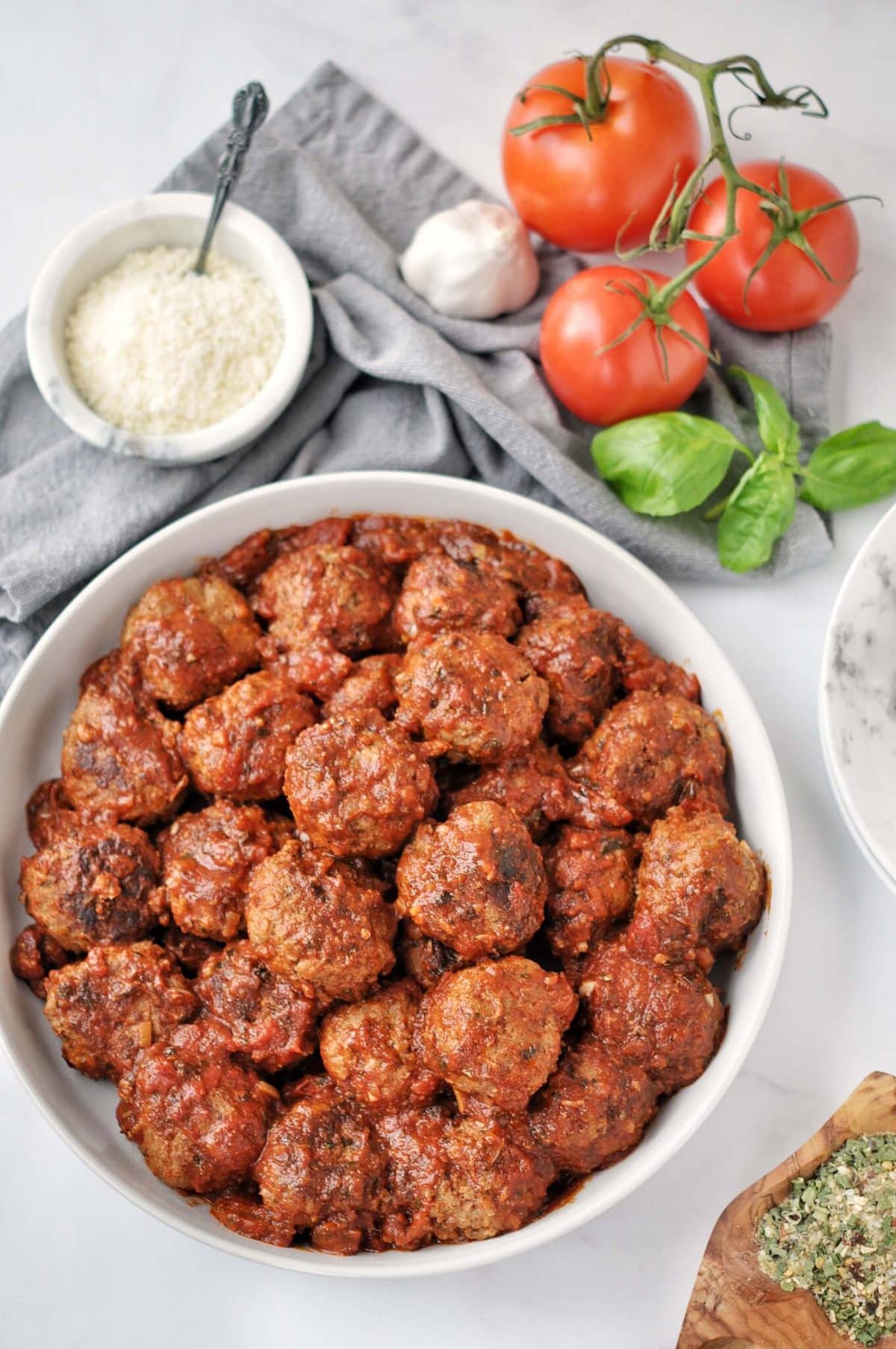 Overhead shot of slow cooked meatballs in tomato sauce. surrounded by fresh ingredients