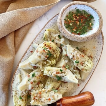 Overhead shot of marinated artichoke heart on a speckled ceramic plate