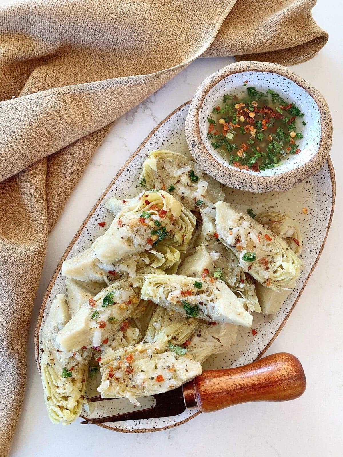 Overhead shot of marinated artichoke heart on a speckled ceramic plate