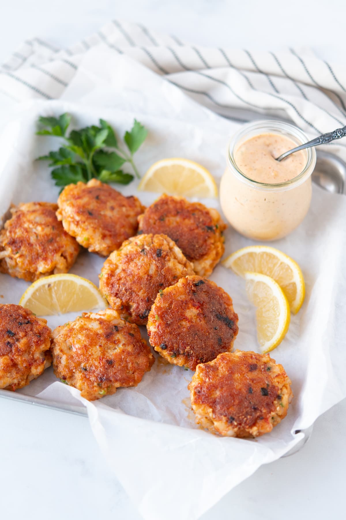 Shrimp cakes surrounded by lemons and parsley, served with remoulade