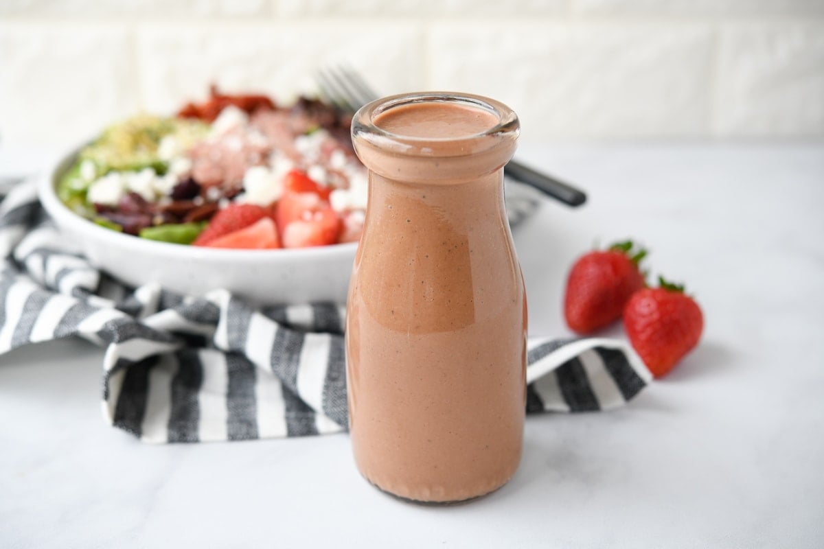 bottle of strawberry balsamic salad dressing with a salad in the background