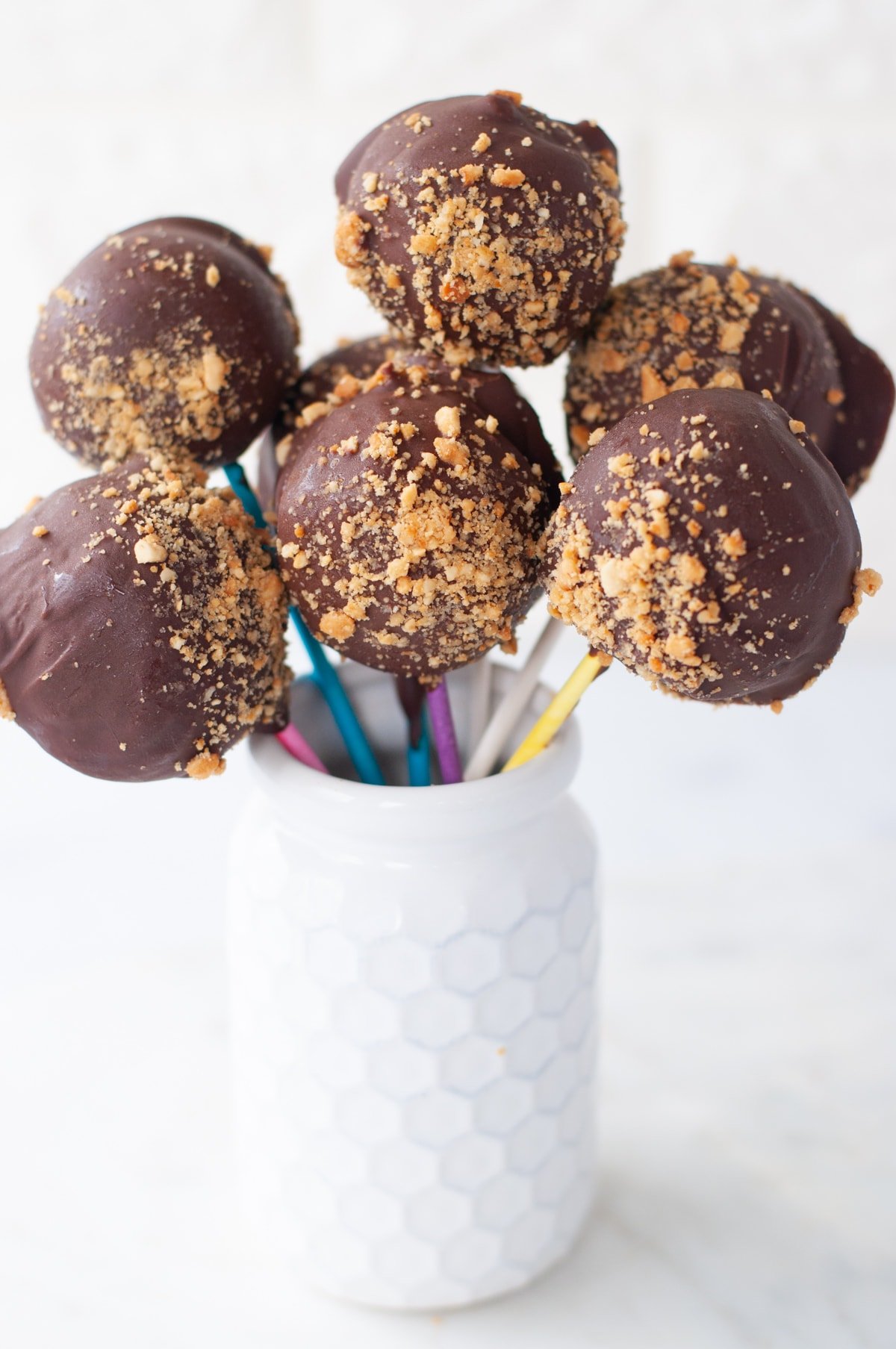 Low Carb Chocolate Peanut Butter Pops on colorful sticks, arranged in a honeycomb pot. 