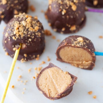 Chocolate Peanut Butter Pops coated in crushed peanuts and lined on a parchment paper lined baking sheet.
