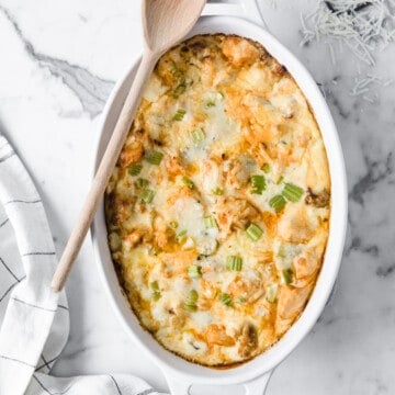 white casserole dish with low carb buffalo chicken Mac and cheese, with a wood serving spoon.