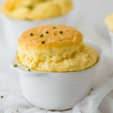Cheese and Chive Keto Souffles in a white ceramic ramekin, sprinkled with fresh chives.