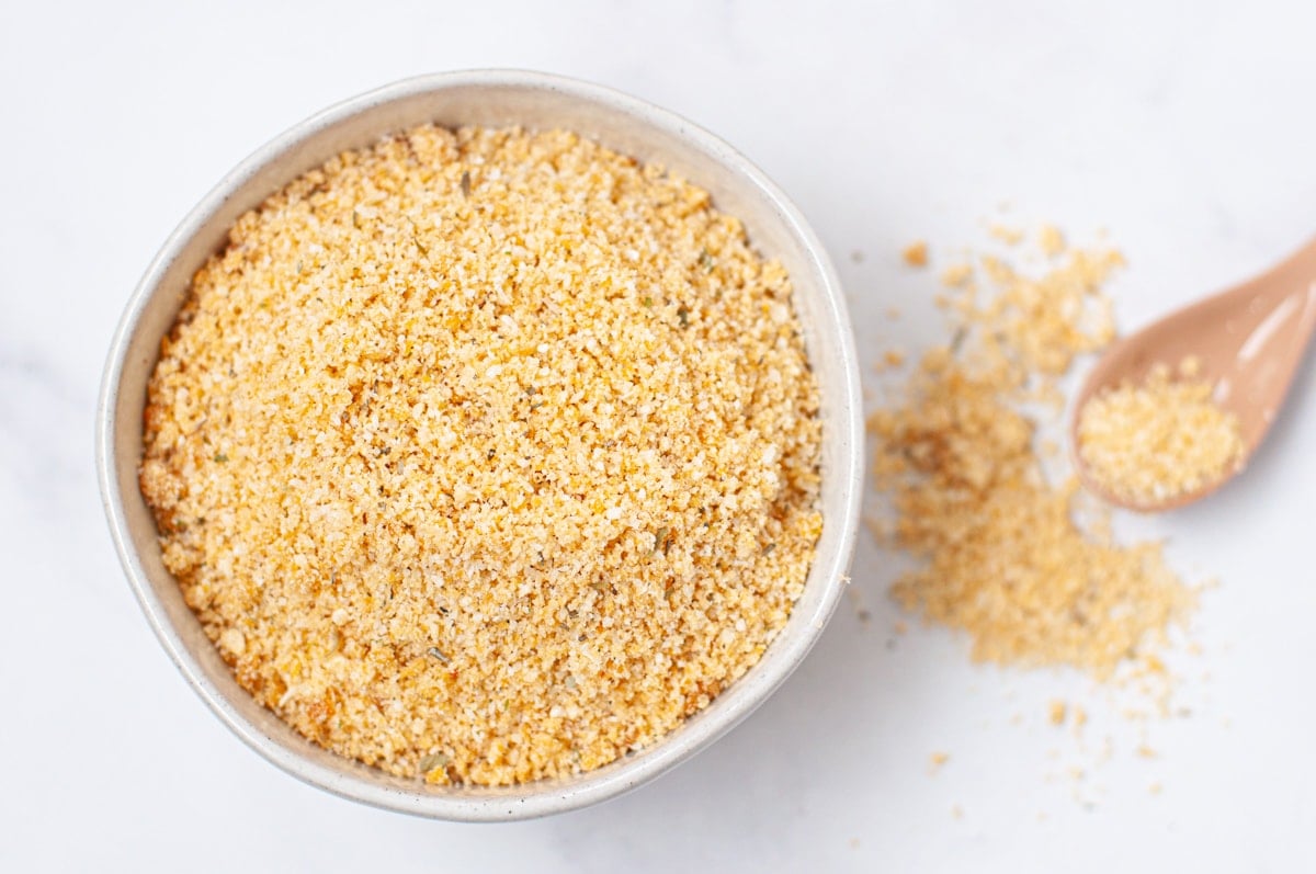 a mixing bowl with crushed pork rinds, parmesan cheese, garlic powder, onion powder, and Italian seasoning