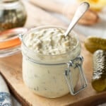 a jar of homemade tartar sauce, surrounded by pickles, and lemons.