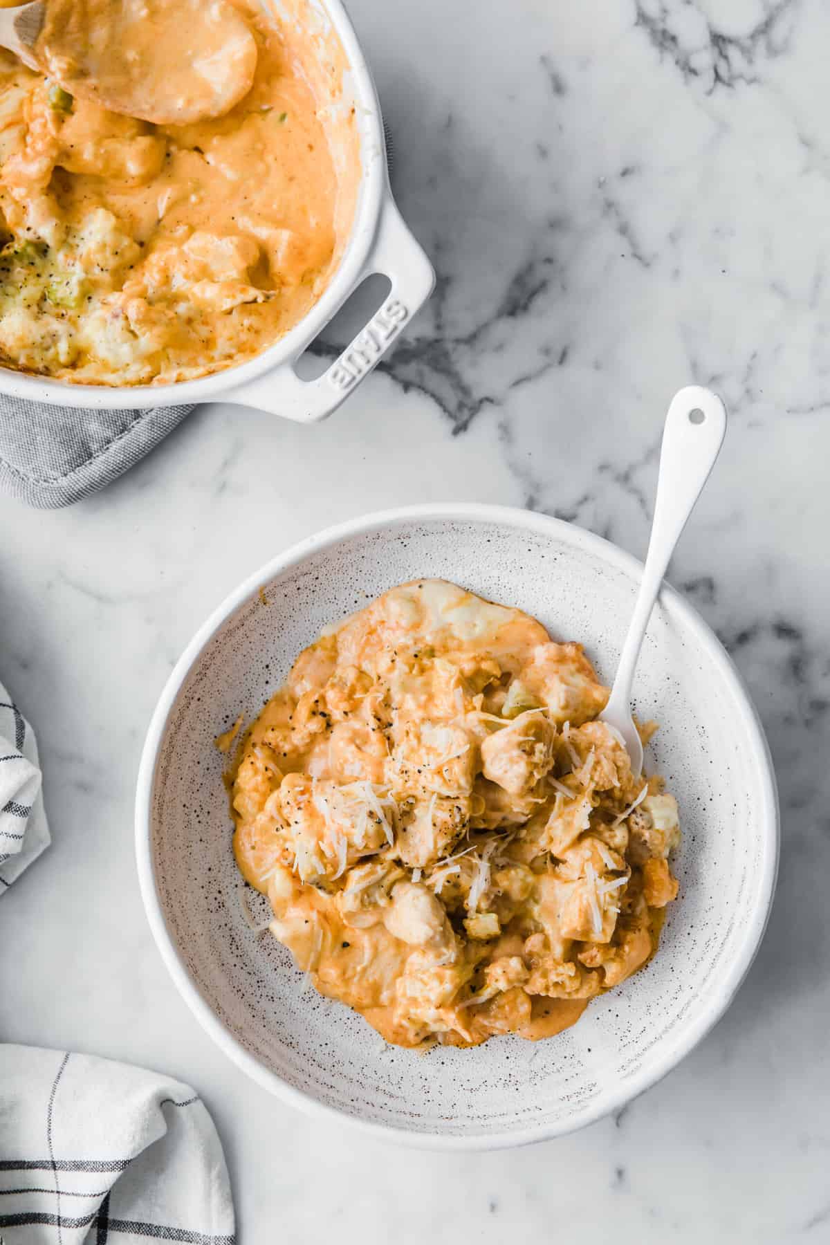 white casserole dish with low carb buffalo chicken Mac and cheese, with a wood serving spoon