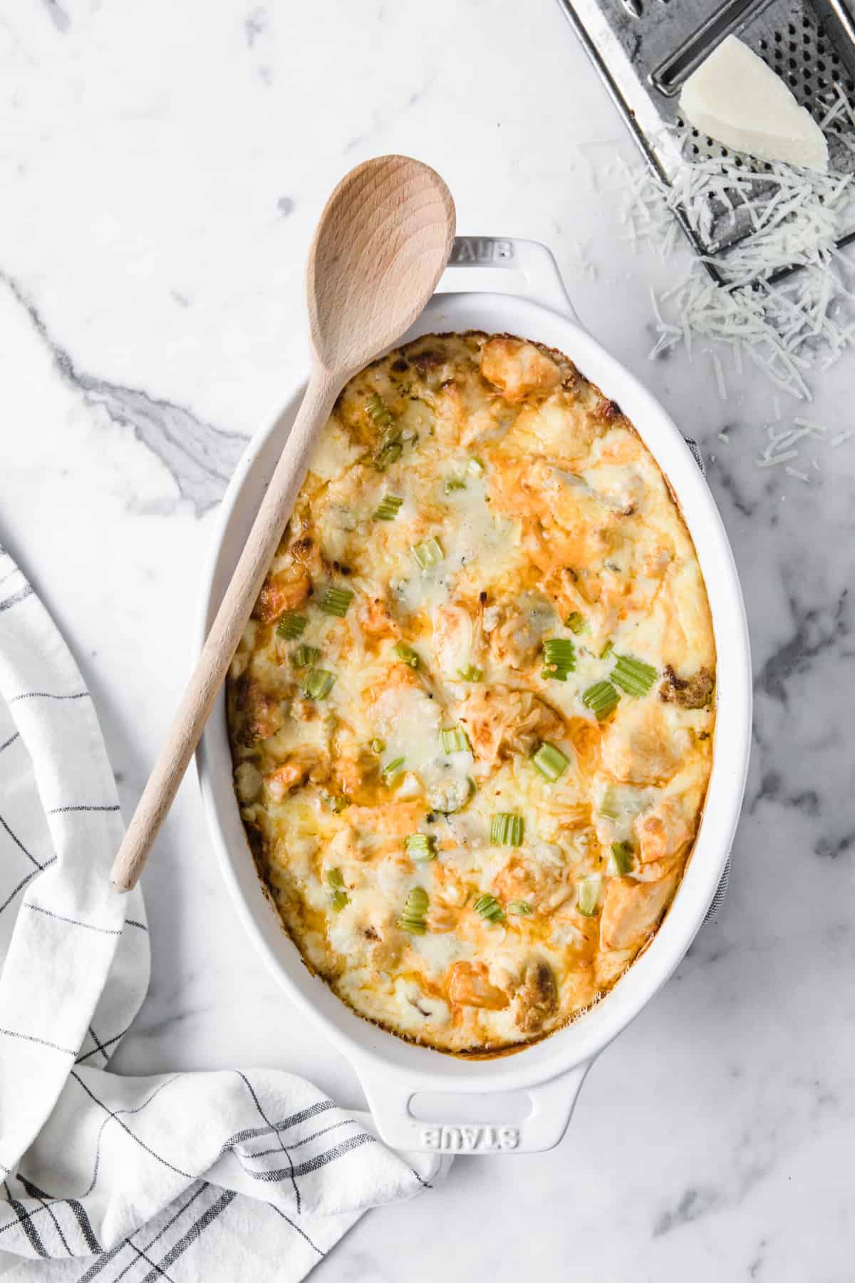 white casserole dish with low carb buffalo chicken Mac and cheese, with a wood serving spoon