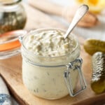 a jar of homemade tartar sauce, surrounded by pickles, and lemons