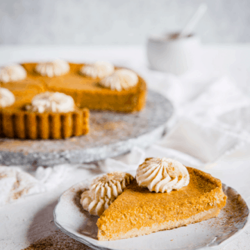 Keto Pumpkin Pie cut into slices and topped with whipped cream and dusted with cinnamon.