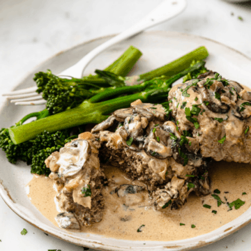 Beef Stroganoff Burgers served with broccolini on a white ceramic plate.