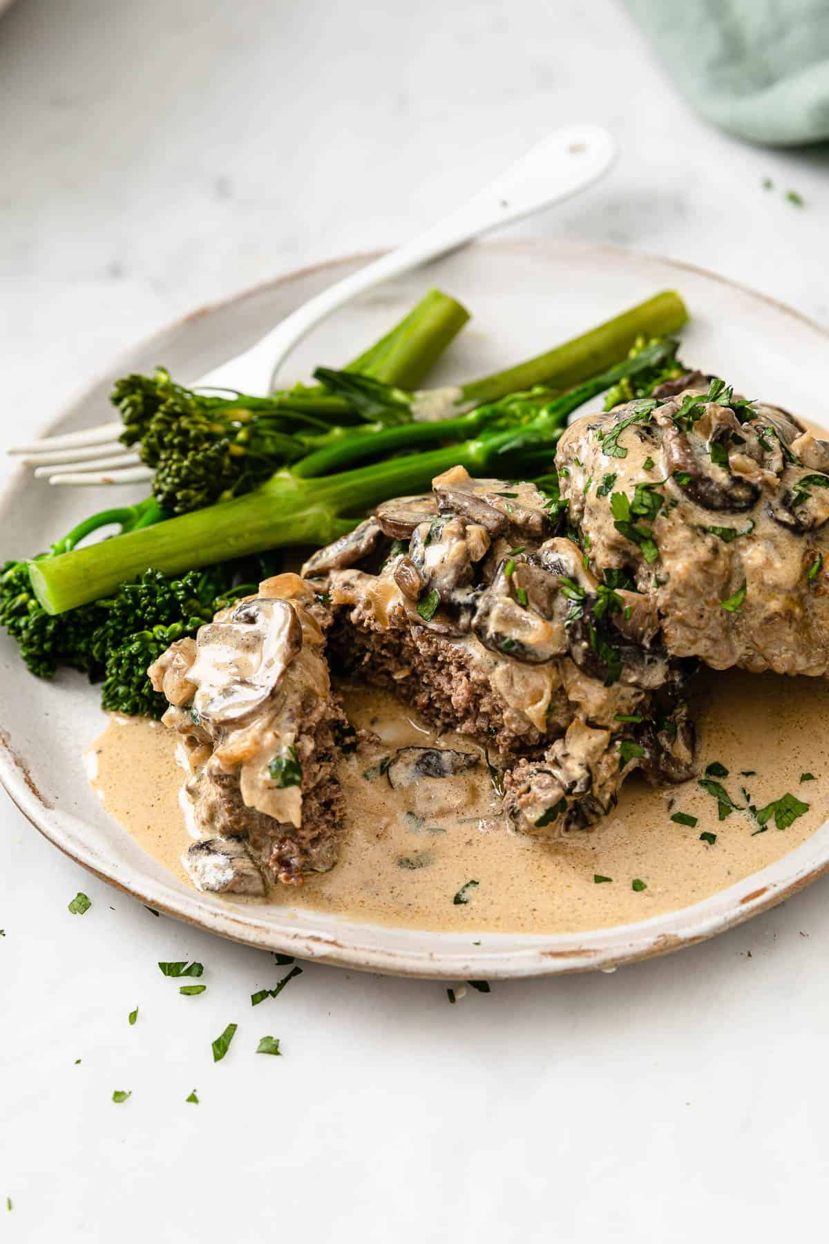 beef stroganoff burgers on a white ceramic plate, served with broccoli
