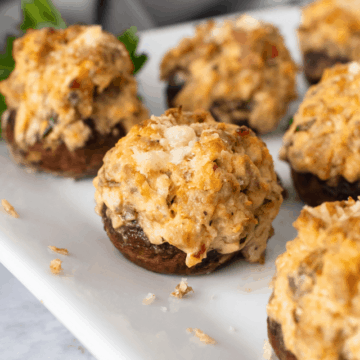 Sausage stuffed mushrooms on a white plate, garnishes with parsley