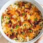 white casserole dish with a twice baked cauliflower with bacon, cheese, and green onions.