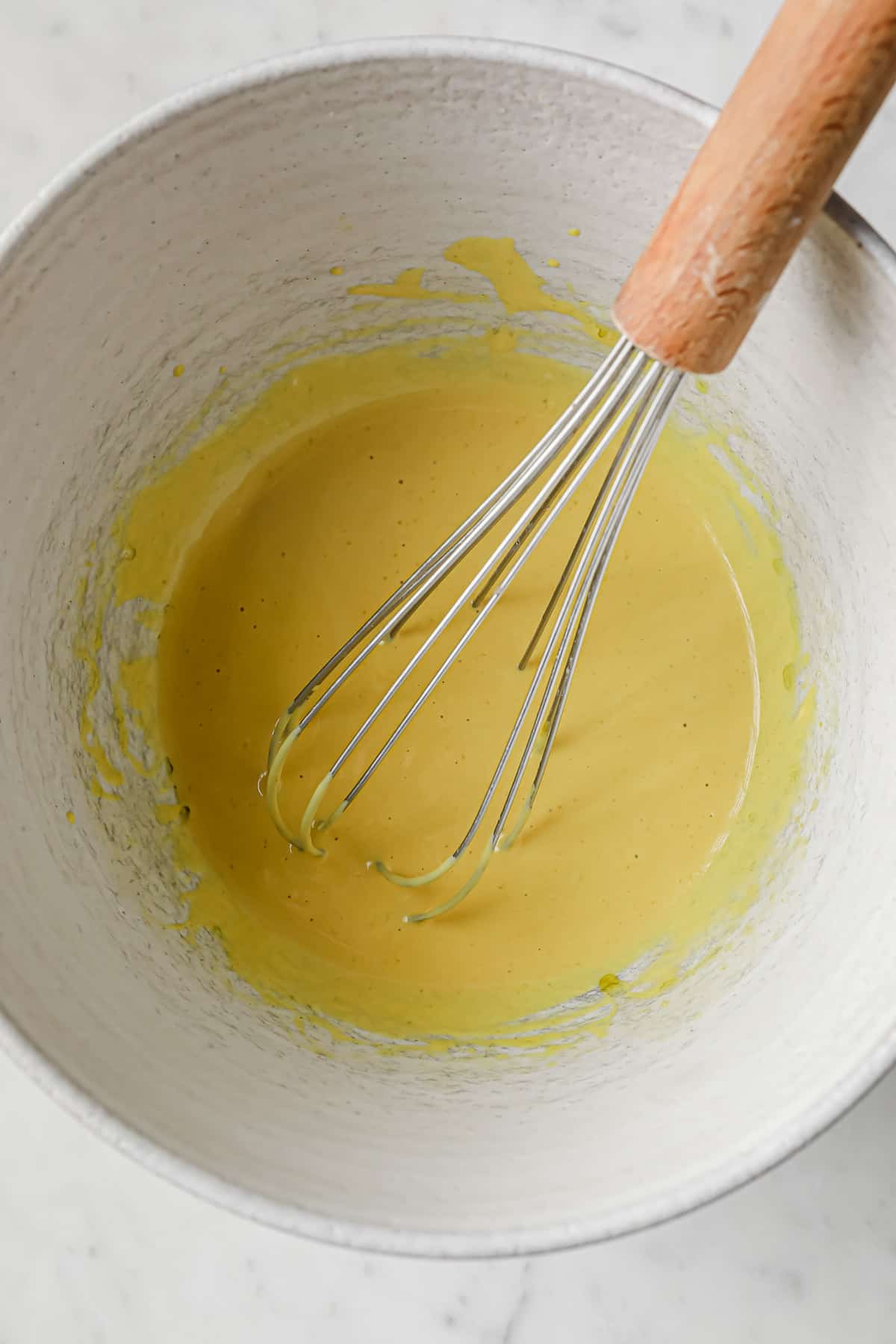 a white ceramic bowl with scratch made salad dressing being whisked